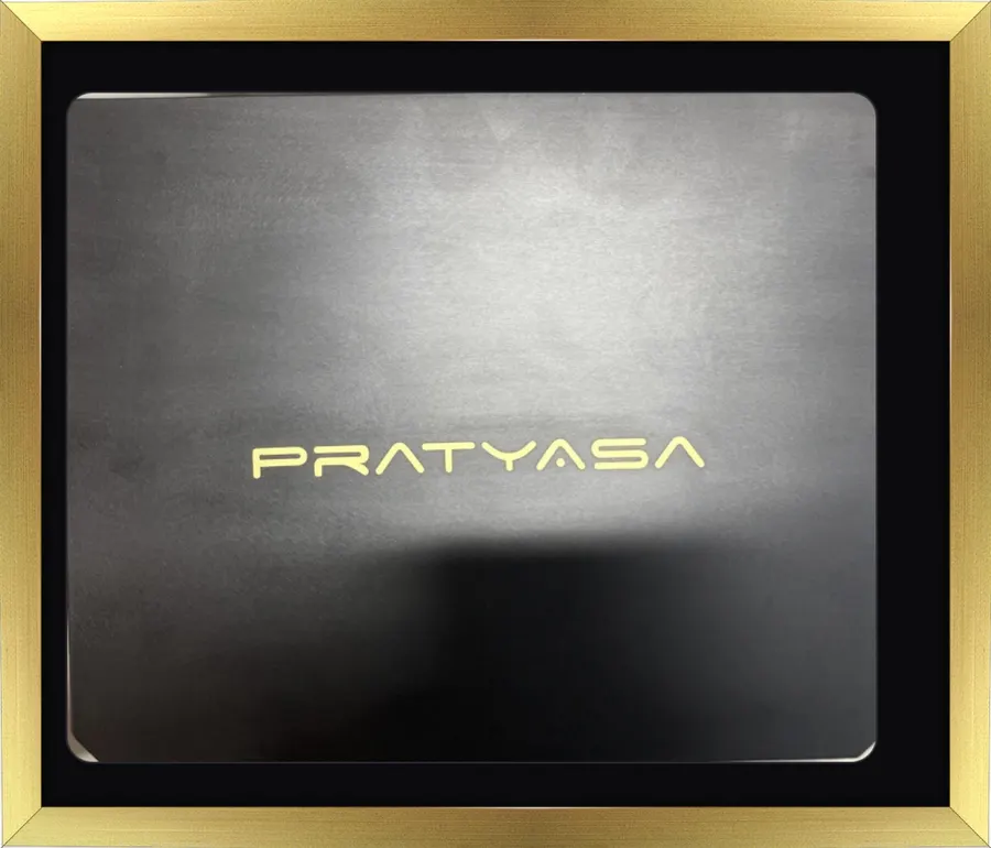 The Pratyasa analyser's black case with its gold wordmark, photographed in a gold frame.